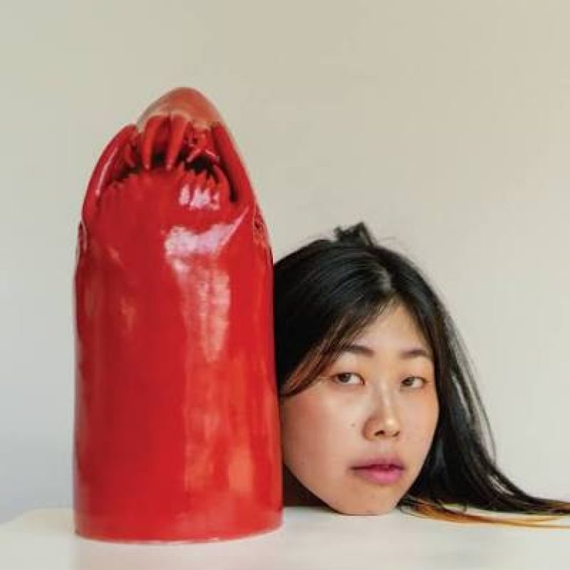 Portrait of the artist Eri Maeda beside one of her ceramics