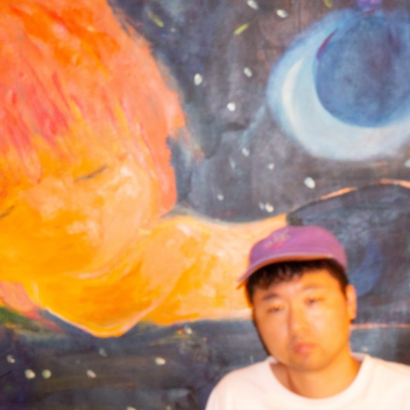 Portrait of the artist Jun Makita in front of one of his paintings